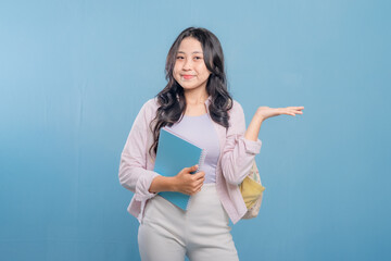 A woman is holding a blue book and pointing to something important. She is smiling and she is happy