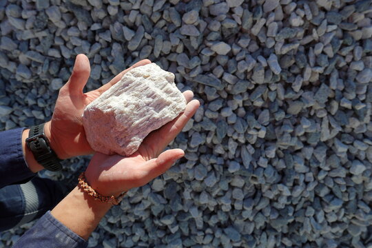 Spodumene ore, lithium bearing mineral, held in hand. Mine, mining of critical minerals, raw materials, for energy transition and storage