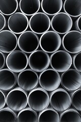Stack of steel pipes arranged neatly, showcasing precision and craftsmanship in a clean studio environment