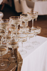 Sparkling vintage-style champagne glasses with gold rims arranged on a sequined and white tablecloth