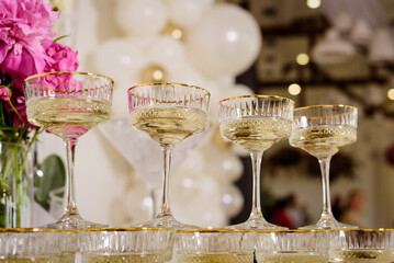 Sparkling vintage-style champagne glasses with gold rims arranged on a sequined and white tablecloth