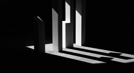 Abstract monochrome architectural forms cast dramatic shadows in a dark space.