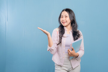 A woman is holding a blue book and pointing to something important. She is smiling and she is happy