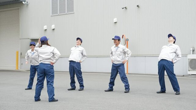 工場の前で体操する作業員グループ