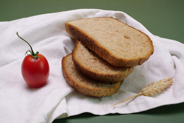 Fette di pane integrale sul tovagliolo, pomodoro e spiga di garno