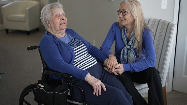 A daughter visits her elderly mother in a cozy home setting, providing care and support while sharing a warm moment together in the living area.