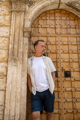 A calm, youthful-looking man between 55 and 60 years old, looking to the side while leaning against...
