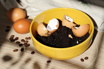 Eggshells and coffee on modern wooden kitchen table with beige towel, eggs and coffee beans on...