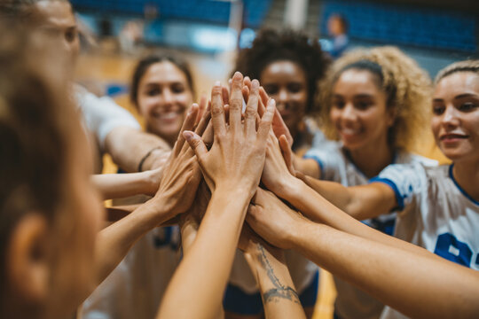 Team of female volleyball players celebrating their victory with a high five in a sports arena during a tournament event