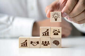 Person placing lightbulb cube on growth teamwork brain wooden blocks