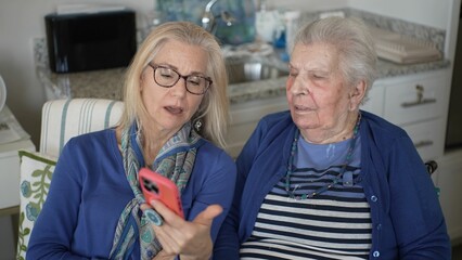 A woman in her 90s enjoys a video chat with her daughter, who shares memories and love,...