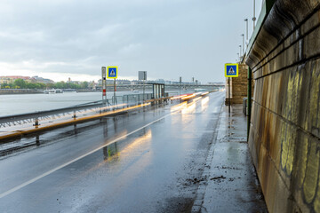 Rainy urban riverside road with blurred light trails from cars