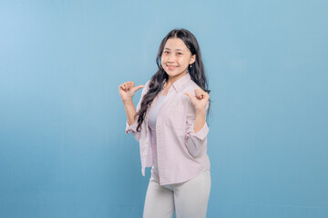 Fototapeta premium A woman is smiling and pointing her finger at the camera. She is wearing a pink shirt and white pants