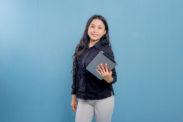 A woman is smiling and holding a tablet. She is wearing a black shirt and white pants. Concept of professionalism and confidence