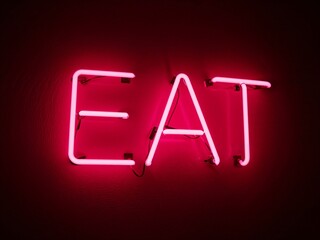 Vintage bar light with pink neon letters spelling Eat