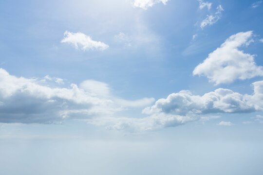 Fototapeta White cumulus clouds are drifting over gradient blue flat design sky with faint haze