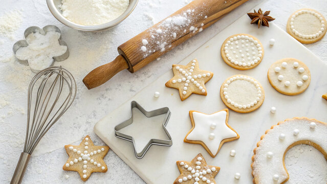 Decorated christmas cookies with baking tools on a marble surface