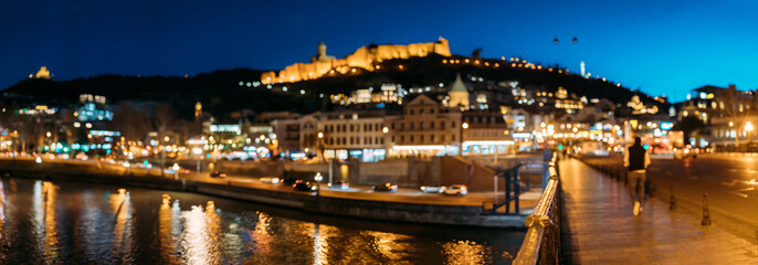 Tbilisi, Georgia. Panoramic Scenic View Of Impregnable Fortress Narikala Fortress, Metekhi Church. Night Boke Bokeh Blurred Ancient Fortress Narikala In Old Town Of Tbilisi. Caucasus. Abstract Blurred