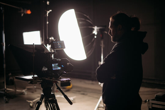 The director of photography with a camera on the set. A professional videographer is working on filming a movie or commercial for a TV series. The filming process takes place indoors in a studio.