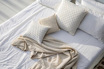 Cozy neutral bedding with textured pillows and blanket
Minimalist bed with cream and beige textured pillows and soft knitted blanket in natural light, evoking comfort and Scandinavian interior style.
