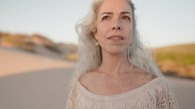 A serene scene of a mature woman embracing her natural beauty, finding peace and enjoying a moment of mindfulness by the ocean.