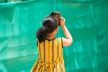 young school girl in yellow frock taking bird photo using mobile phone. childhood curiosity, digital learning, and joy of exploring nature. themes of technology, childhood, education, creativity. 