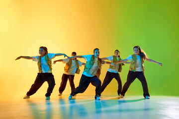 Young dancers embody urban culture with an energetic group performance on a vibrant colored...