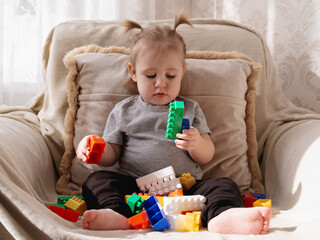 Little toddler sits with colorful building blocks but shows no emotional engagement, highlighting early signs of possible autism