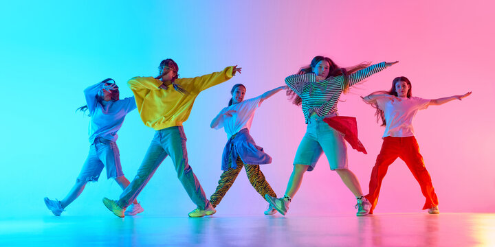 Youthful dancers showcase vibrant urban style with dynamic poses and colorful background lighting. Concept of modern street dance expression and energetic creativity.