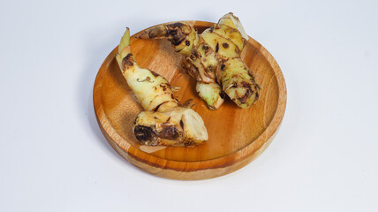 Galangal Roots Presentation: Galangal roots are delicately presented on a wooden plate in a studio setup, highlighting their earthy tones and unique textures in a photo-realistic composition.