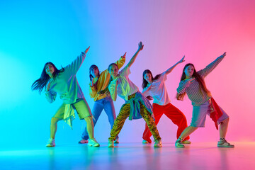 Youthful dancers express vibrant urban energy in a colorful, illuminated studio setting. Concept of...