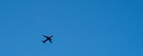 The passenger airplane is flying far away in blue sky.