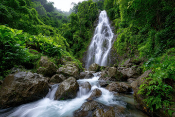 Naklejka premium Serene waterfall cascading through lush green forest at midday
