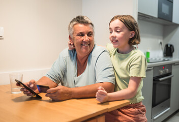 Smiling caucasian grandmother and granddaughter enjoying time together with smartphone.	