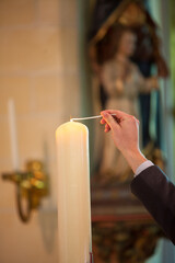 A hand delicately lighting a candle in a serene and tranquil church, beautifully symbolizing faith...