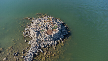 Ancient nuraghe ruins partially submerged in a Sardinian lake, exposed by low water