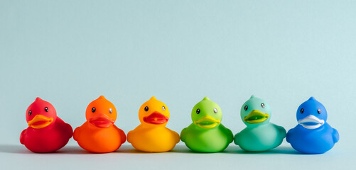 Colorful rubber ducks in rainbow order on a light blue background. Minimalist composition, symbol...