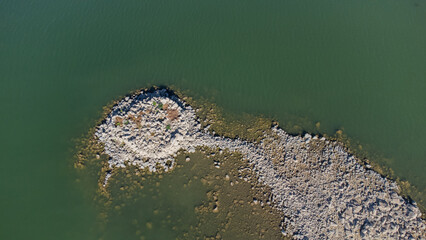Ancient nuraghe ruins partially submerged in a Sardinian lake, exposed by low water