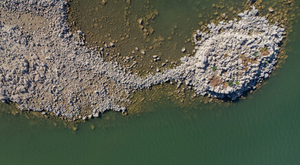 Ancient nuraghe ruins partially submerged in a Sardinian lake, exposed by low water