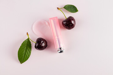 A beautiful package of lip balm or lipstick lies on sample of the texture of the product among ripe...