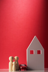 Wooden house with car and wooden peg dolls on red background