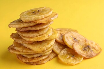 Stacked Fried Plantain Chips on Yellow Background – Crispy Tropical Snack Food Concept.
