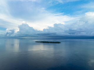 A serene sunrise silhouettes an island within Wakatobi National Park, off the coast of Sulawesi. This area is a popular destination for divers and snorkelers due to its high marine biodiversity.