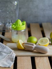 several lemons and limes squeezed on a wooden table to prepare a fresh summer lemonade