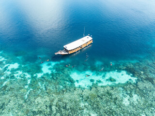 Snorkelers explore the edge of a coral reef within Wakatobi National Park, off the coast of Sulawesi. This area is a popular destination for divers and snorkelers due to its high marine biodiversity.