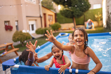 Children playing and enjoying a summer day in a backyard swimming pool