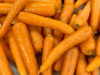 Heap of fresh orange carrots with natural texture, ideal for food and market concepts.