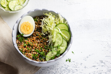 Nutritious buckwheat bowl with fresh cucumber, cabbage, and egg, copy space