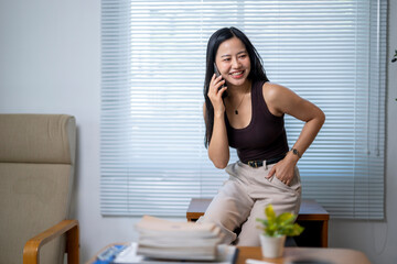 A woman is sitting on a chair and talking on her cell phone