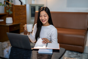 A woman is sitting at a table with a laptop and a notebook
